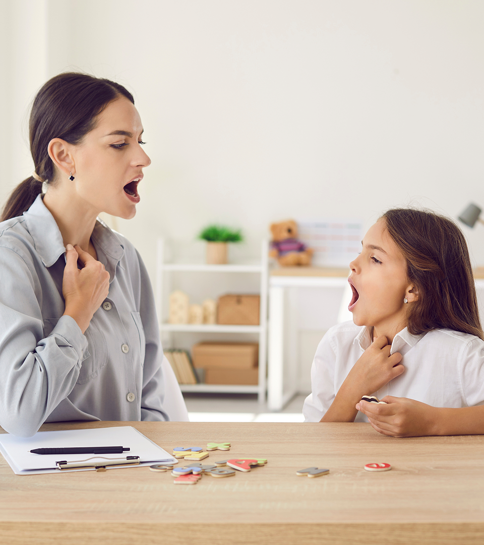 Speech therapist and child doing exercises with mouths open